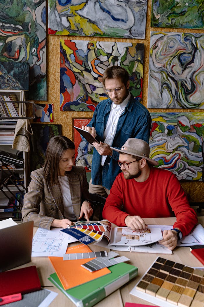 Three designers working together on a project with art in the background, showcasing creativity and teamwork.